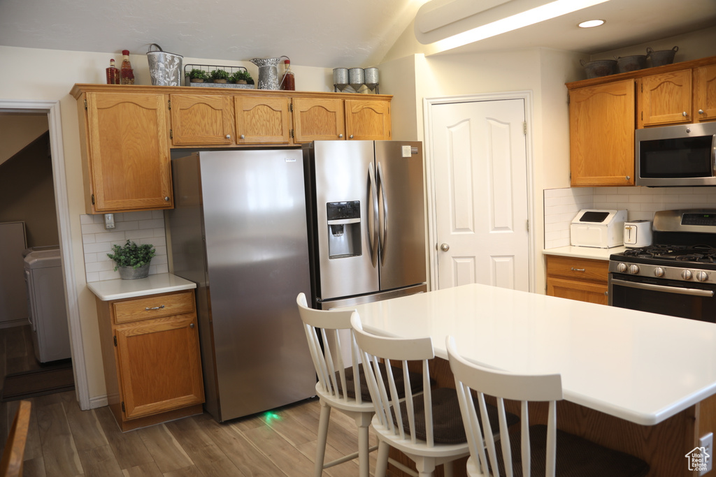 Kitchen with tasteful backsplash, a kitchen breakfast bar, dark hardwood / wood-style floors, and stainless steel appliances
