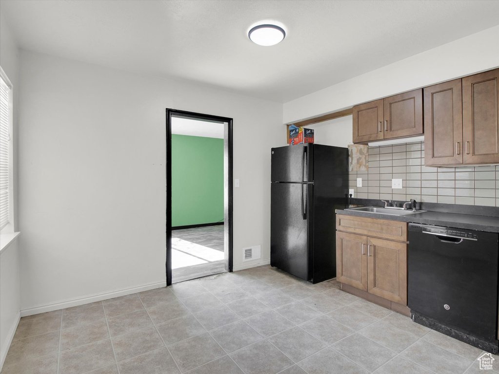 Kitchen featuring sink, tasteful backsplash, light tile floors, and black appliances