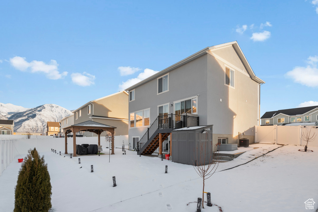 Snow covered rear of property featuring central air condition unit, a gazebo, a patio area, and a mountain view