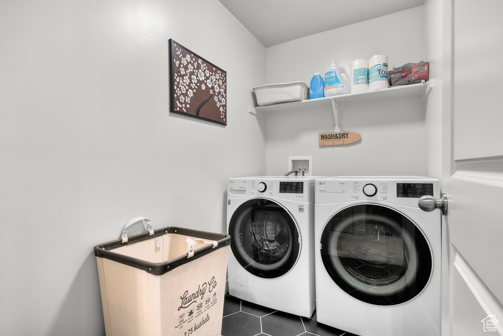 Clothes washing area with independent washer and dryer, dark tile flooring, and washer hookup