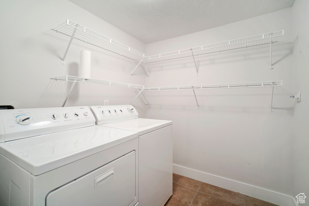 Washroom with washing machine and clothes dryer and dark tile floors