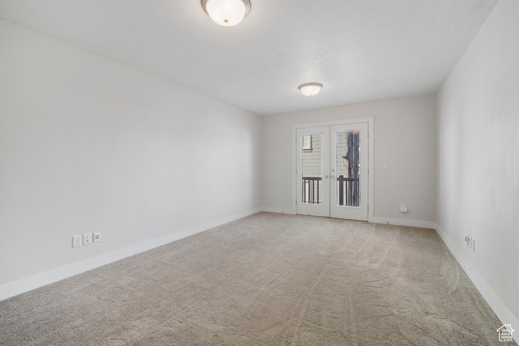 Empty room with light colored carpet and french doors