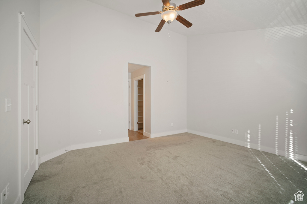 Carpeted empty room with a towering ceiling and ceiling fan