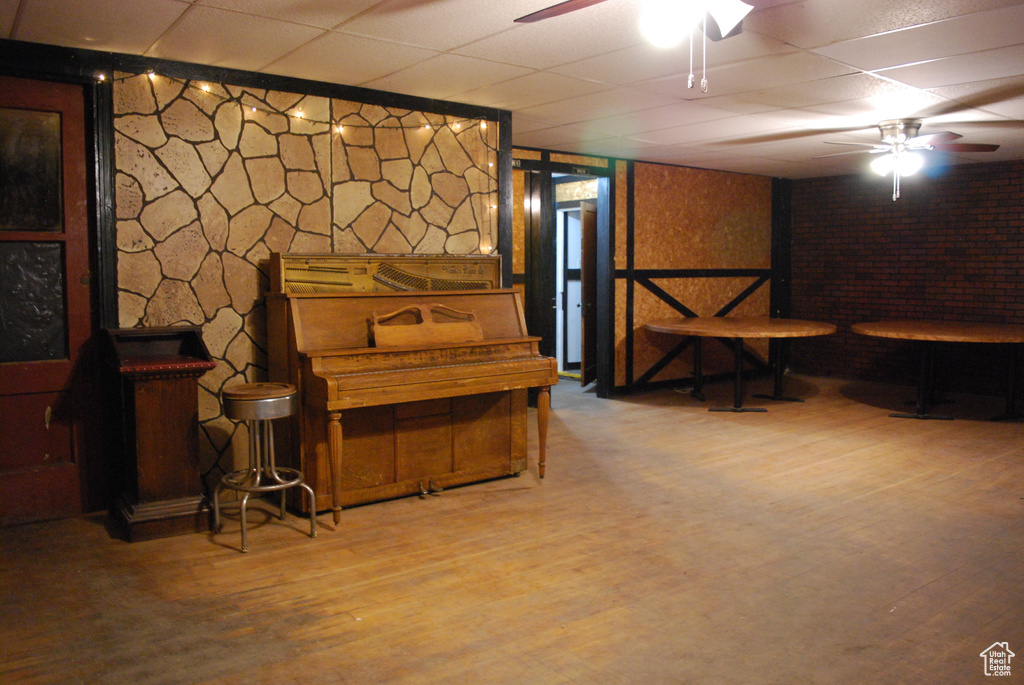 Basement featuring wood-type flooring, a paneled ceiling, and ceiling fan