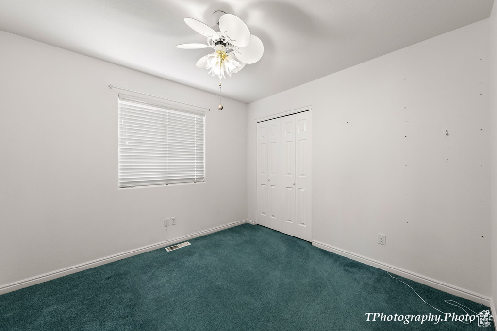 Spare room with dark carpet and ceiling fan
