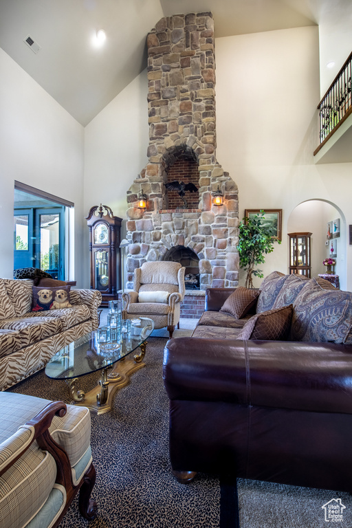 Living room with carpet, a fireplace, and high vaulted ceiling