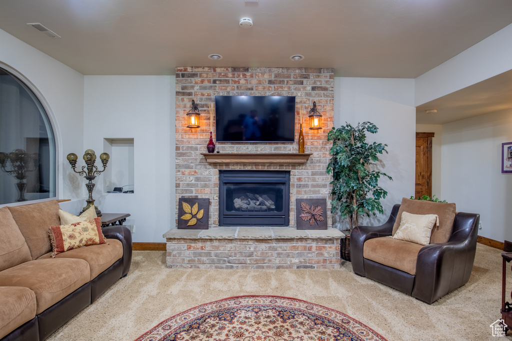Living room with carpet floors, a brick fireplace, and brick wall