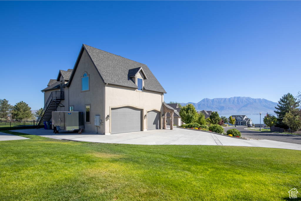 View of property exterior with a garage, a lawn, and a mountain view