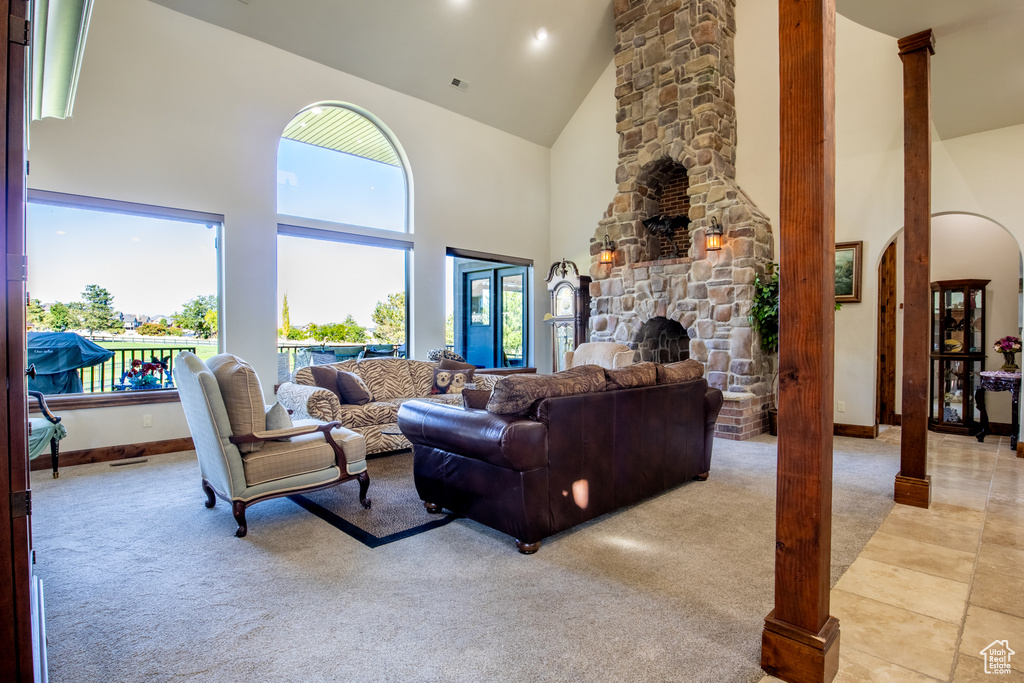 Living room featuring a stone fireplace, high vaulted ceiling, and light colored carpet