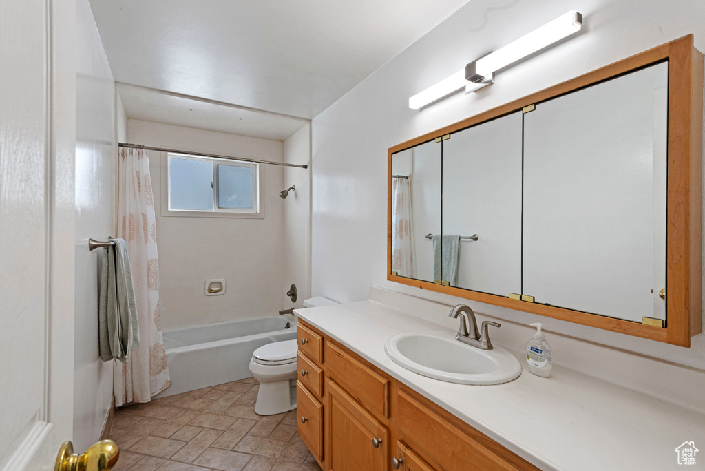 Full bathroom with tile floors, large vanity, shower / tub combo, and toilet