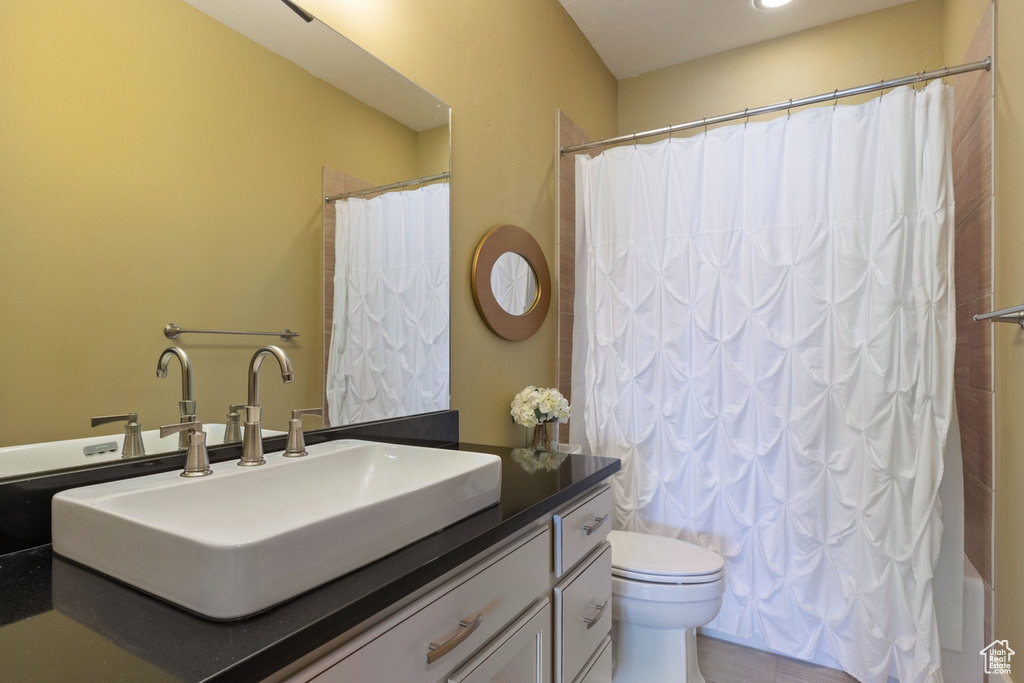 Full bathroom featuring vanity, toilet, and shower / bathtub combination with curtain
