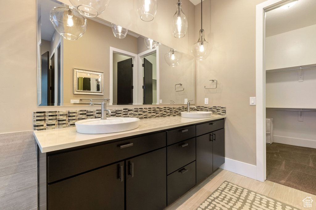 Bathroom featuring tile flooring, dual bowl vanity, and backsplash