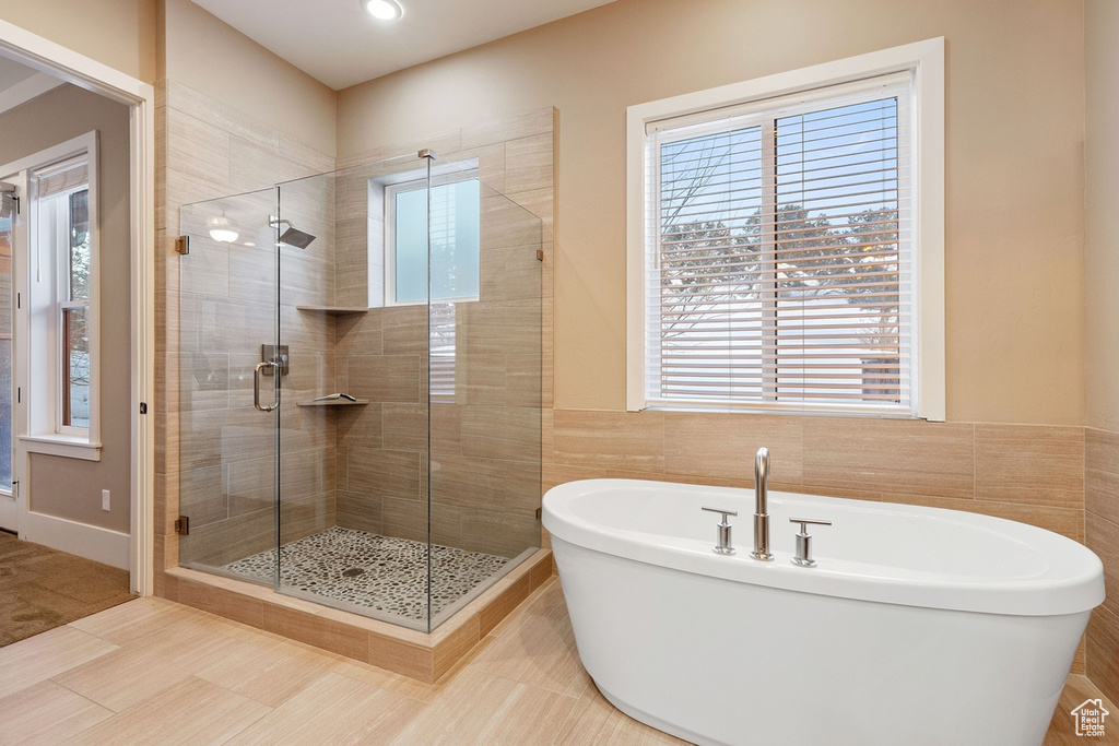 Bathroom featuring tile floors, tile walls, and separate shower and tub