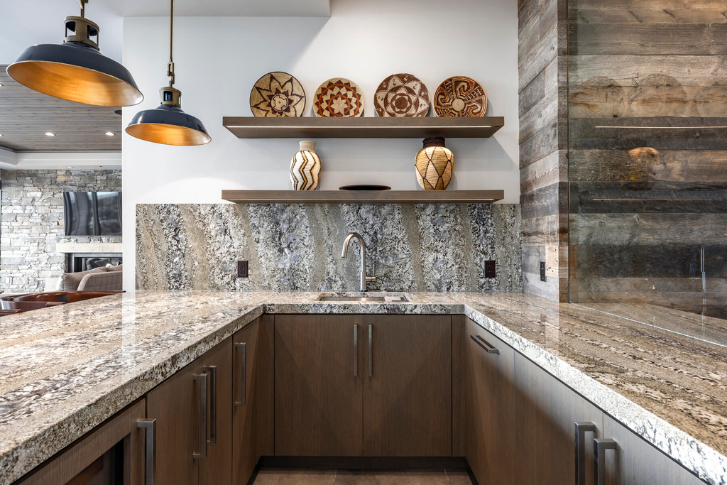 Kitchen with light stone countertops, sink, decorative light fixtures, a fireplace, and dark brown cabinetry