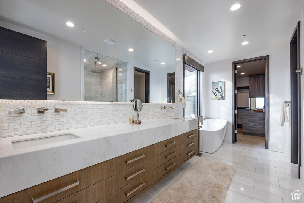 Bathroom featuring tasteful backsplash, dual bowl vanity, tile flooring, and a tub