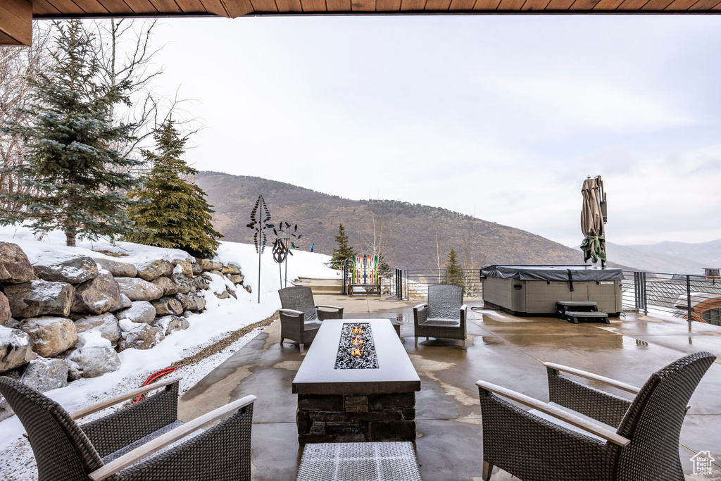 Snow covered patio with a mountain view and an outdoor living space with a fire pit