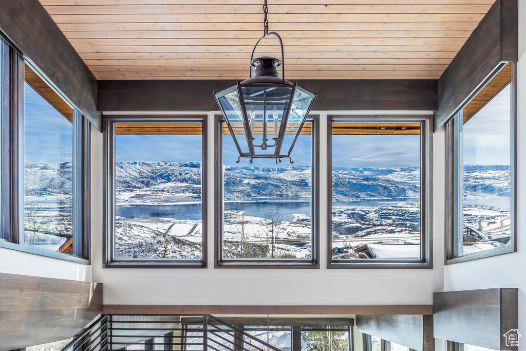 Room details with a mountain view, wood walls, a notable chandelier, and wooden ceiling