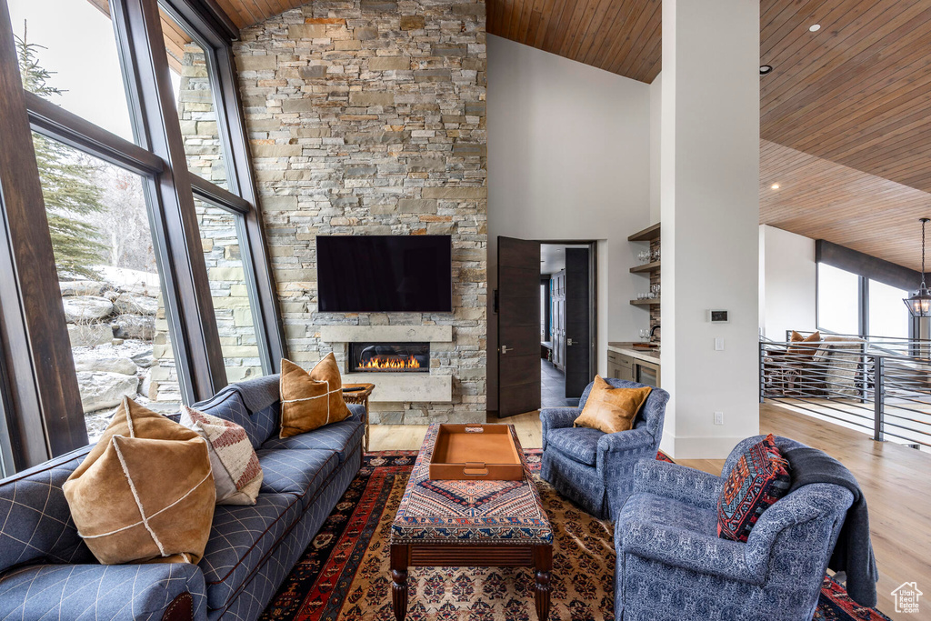 Living room featuring high vaulted ceiling, wooden ceiling, a stone fireplace, and dark hardwood / wood-style floors