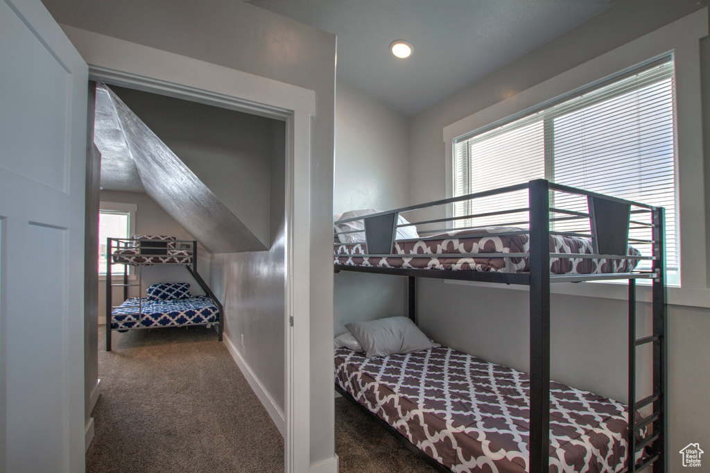 Bedroom with multiple windows, dark carpet, and lofted ceiling