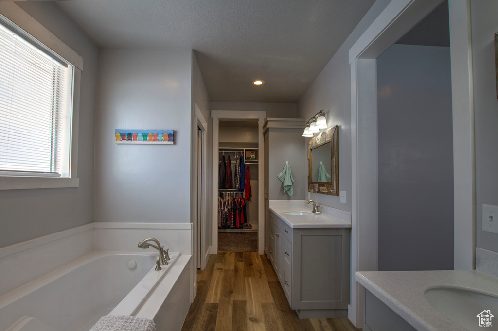 Bathroom with wood-type flooring, a bathtub, and dual bowl vanity