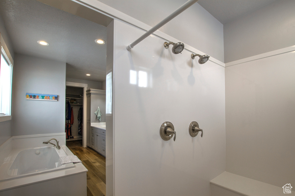 Bathroom featuring wood-type flooring, vanity, and shower with separate bathtub