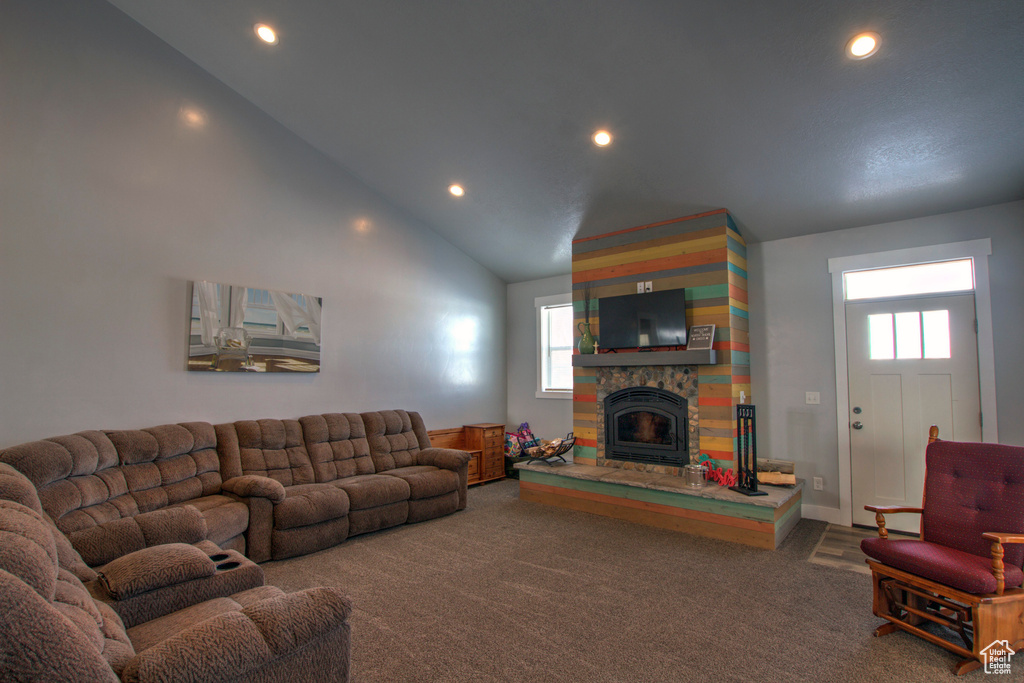 Living room featuring a stone fireplace, dark carpet, and high vaulted ceiling