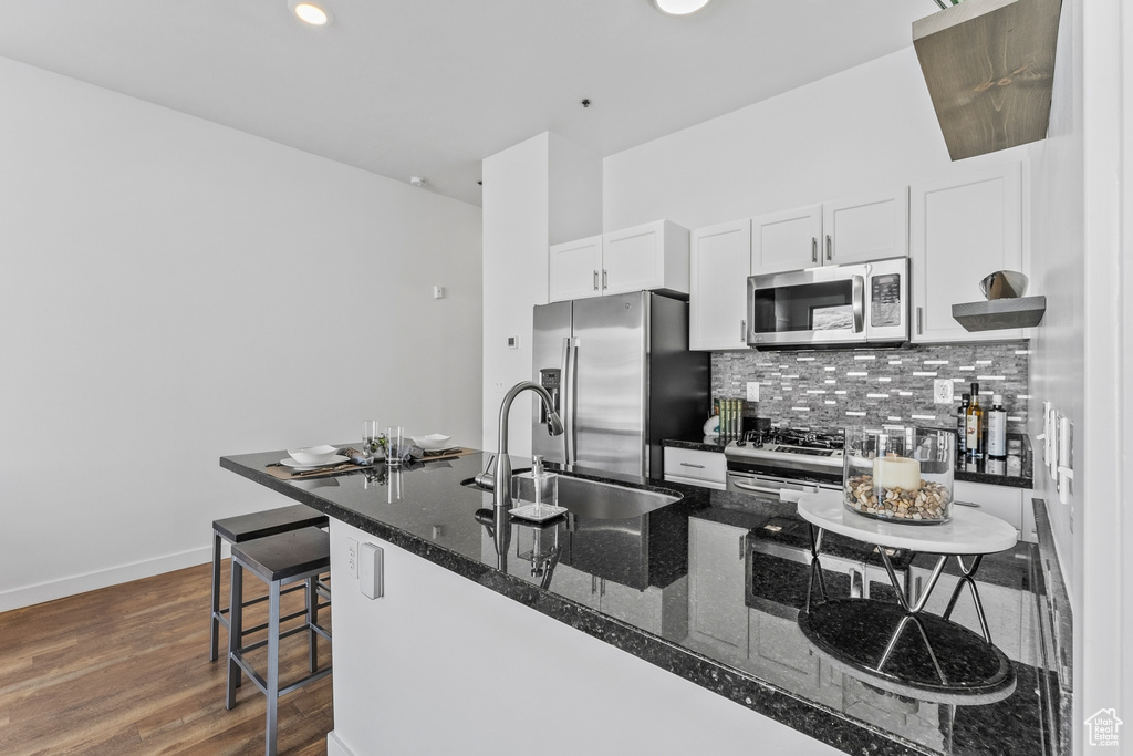 Kitchen with backsplash, white cabinets, sink, dark hardwood / wood-style floors, and stainless steel appliances