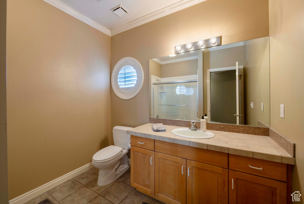 Bathroom with tile floors, ornamental molding, toilet, and vanity with extensive cabinet space