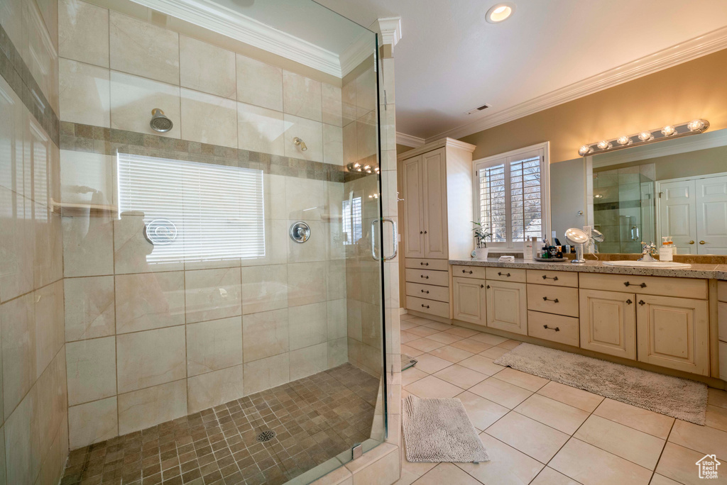 Bathroom featuring double vanity, ornamental molding, a shower with door, and tile flooring