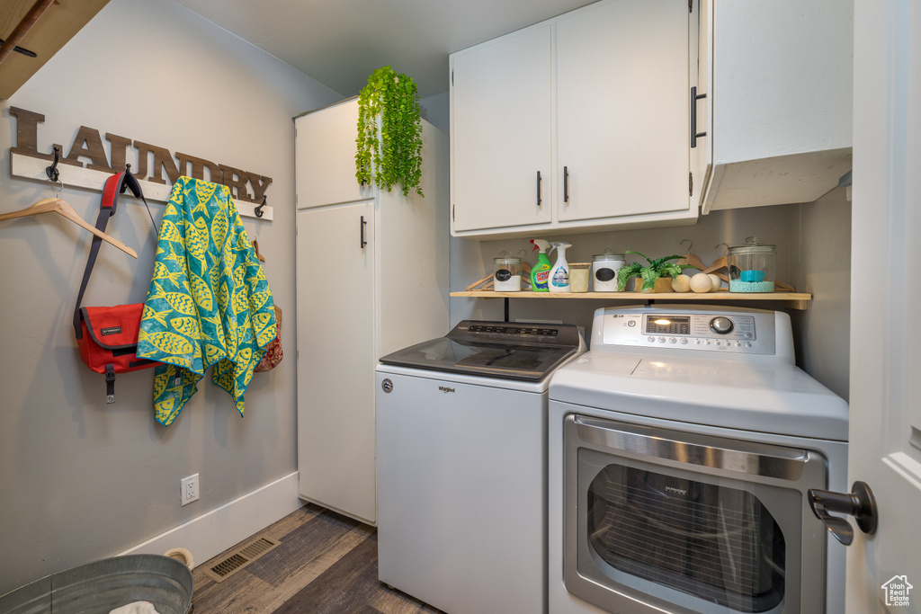Laundry area featuring washing machine and clothes dryer, dark hardwood / wood-style floors, and cabinets