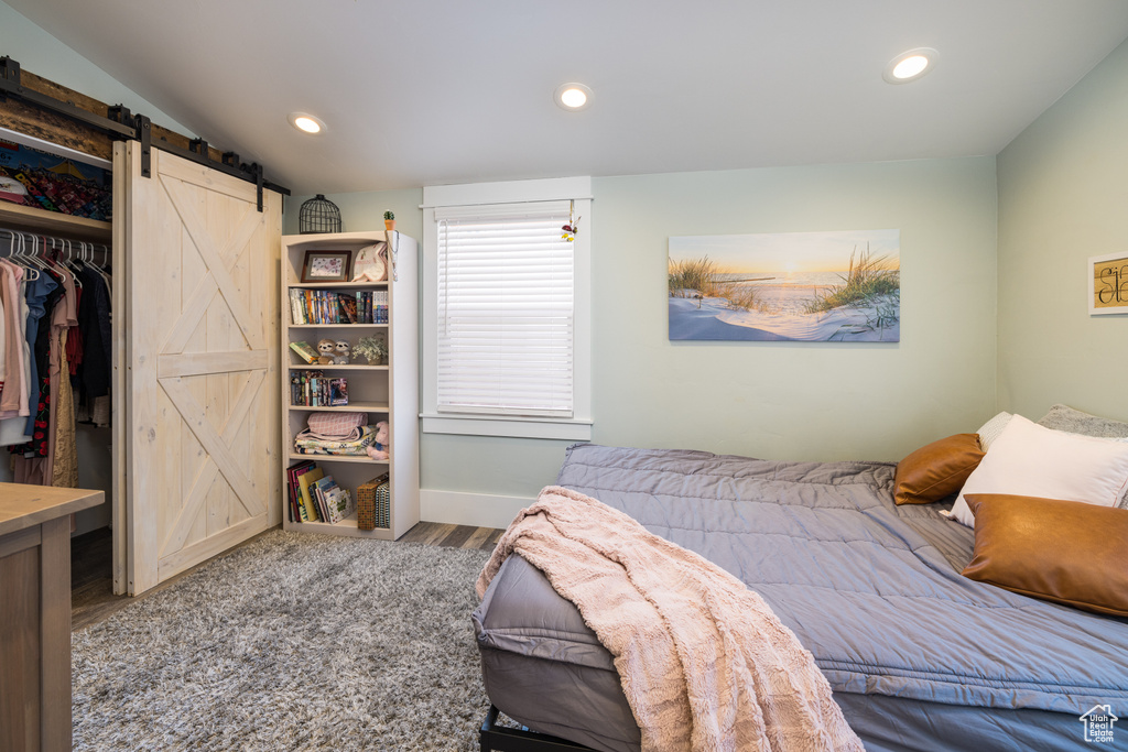Bedroom with a closet, dark hardwood / wood-style floors, and a barn door