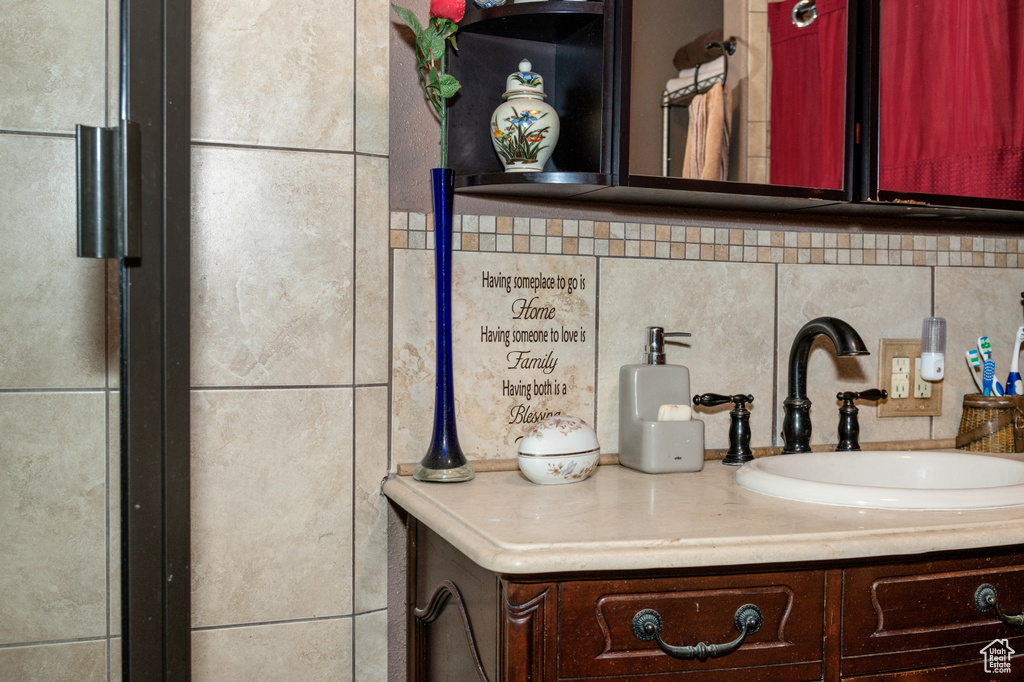 Bathroom featuring tasteful backsplash, tile walls, and vanity