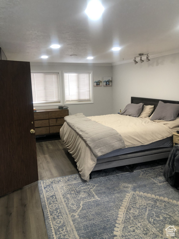 Bedroom with crown molding and dark wood-type flooring
