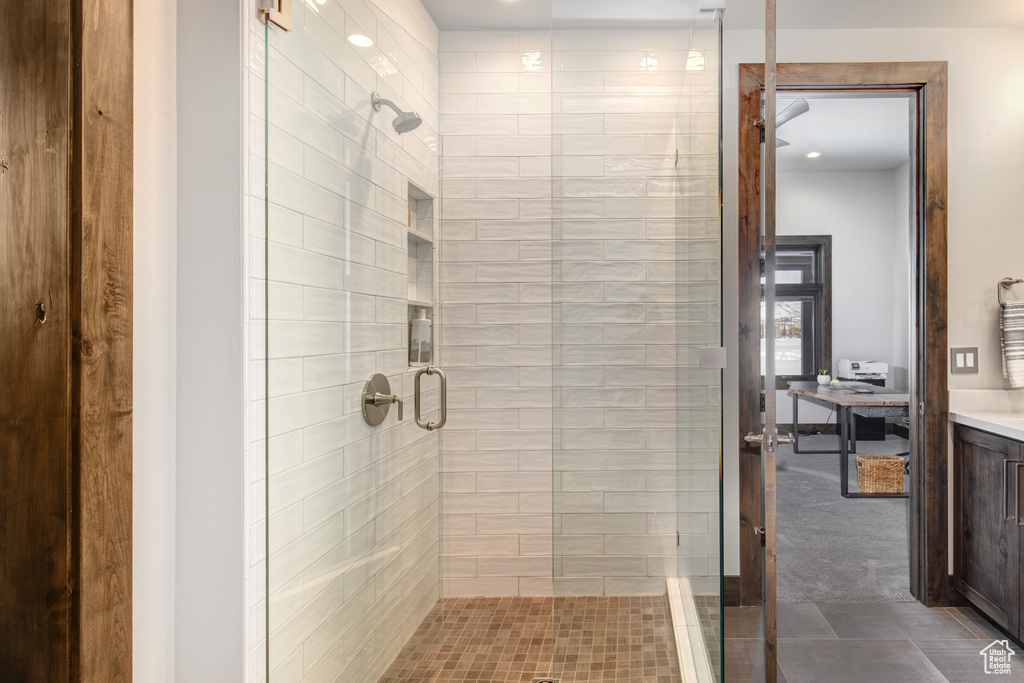 Bathroom featuring a shower with shower door, vanity, and tile flooring