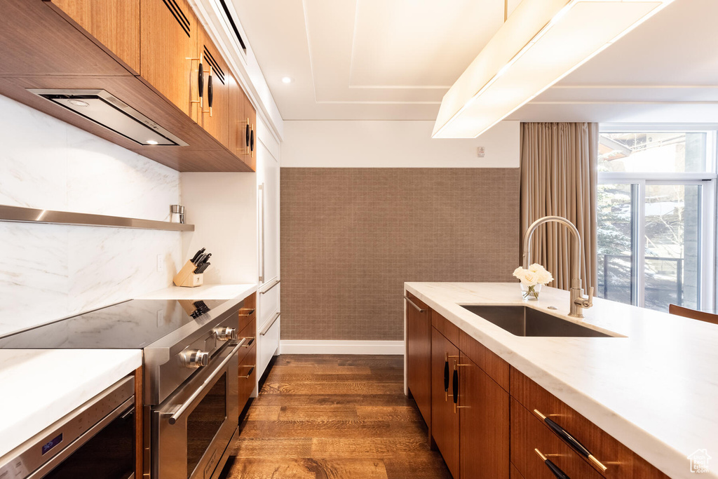 Kitchen featuring dark hardwood / wood-style flooring, sink, stainless steel range, and tile walls