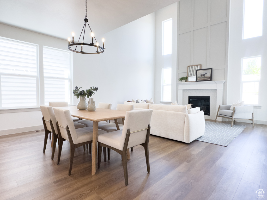 Dining space featuring a towering ceiling, an inviting chandelier, and hardwood / wood-style floors