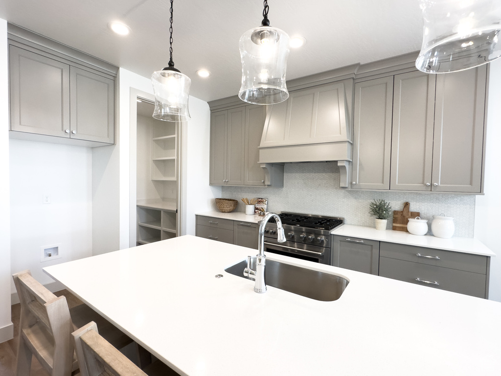 Kitchen featuring stainless steel range, custom exhaust hood, pendant lighting, backsplash, and gray cabinetry
