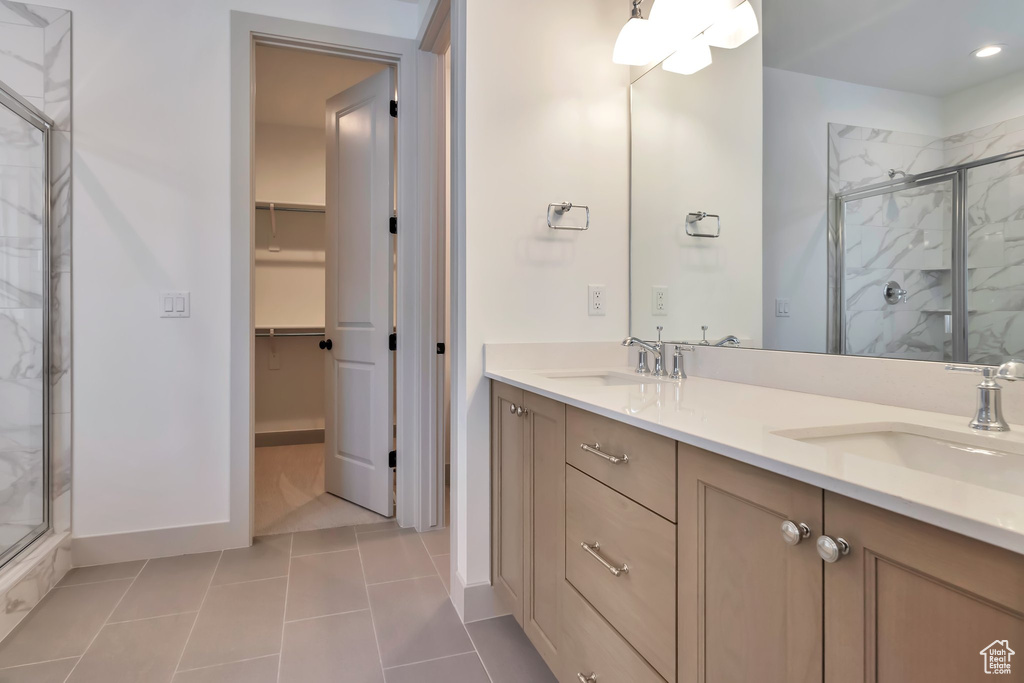 Bathroom with tile floors, double vanity, and a shower with door