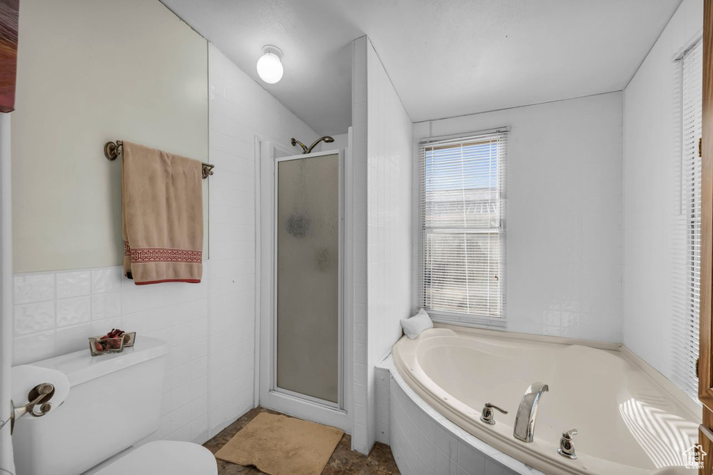 Bathroom featuring tile floors, toilet, plus walk in shower, and tile walls