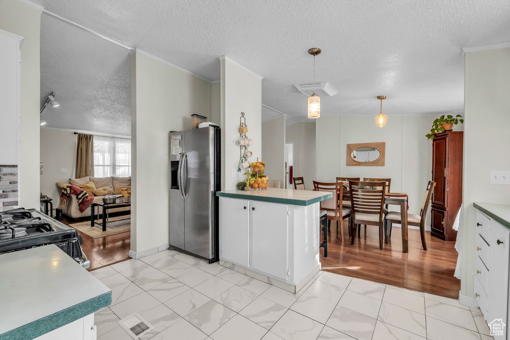 Kitchen featuring pendant lighting, white cabinets, stainless steel fridge, and light tile flooring