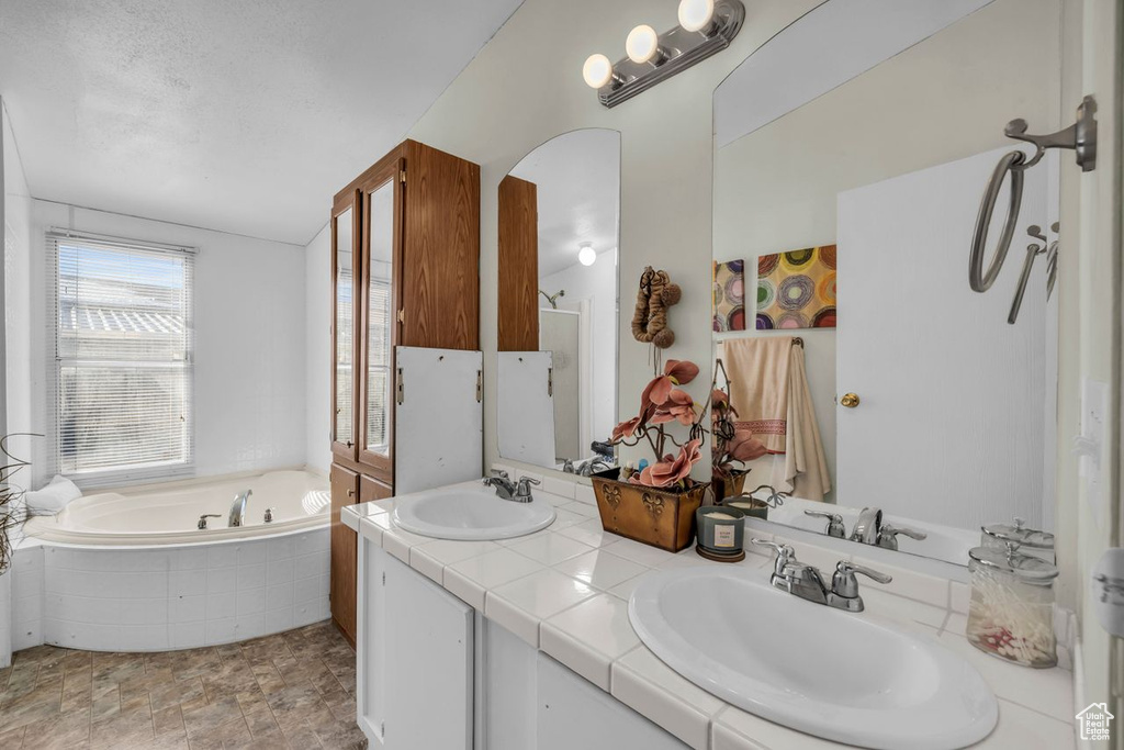 Bathroom with oversized vanity, a bathtub, tile flooring, and double sink
