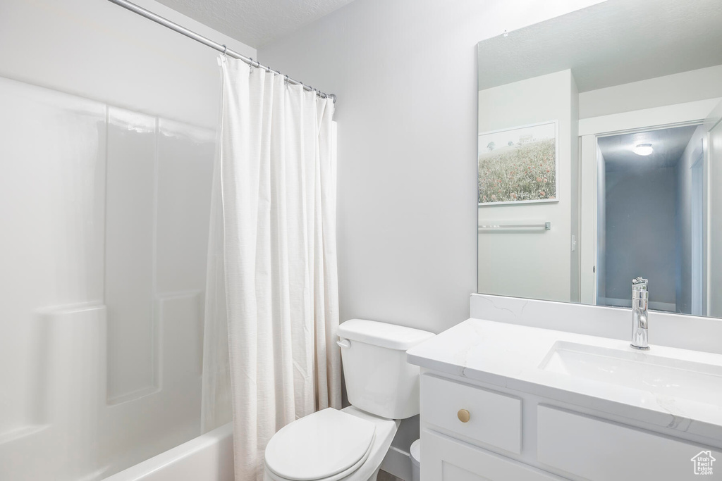Full bathroom featuring vanity with extensive cabinet space, toilet, and shower / tub combo with curtain