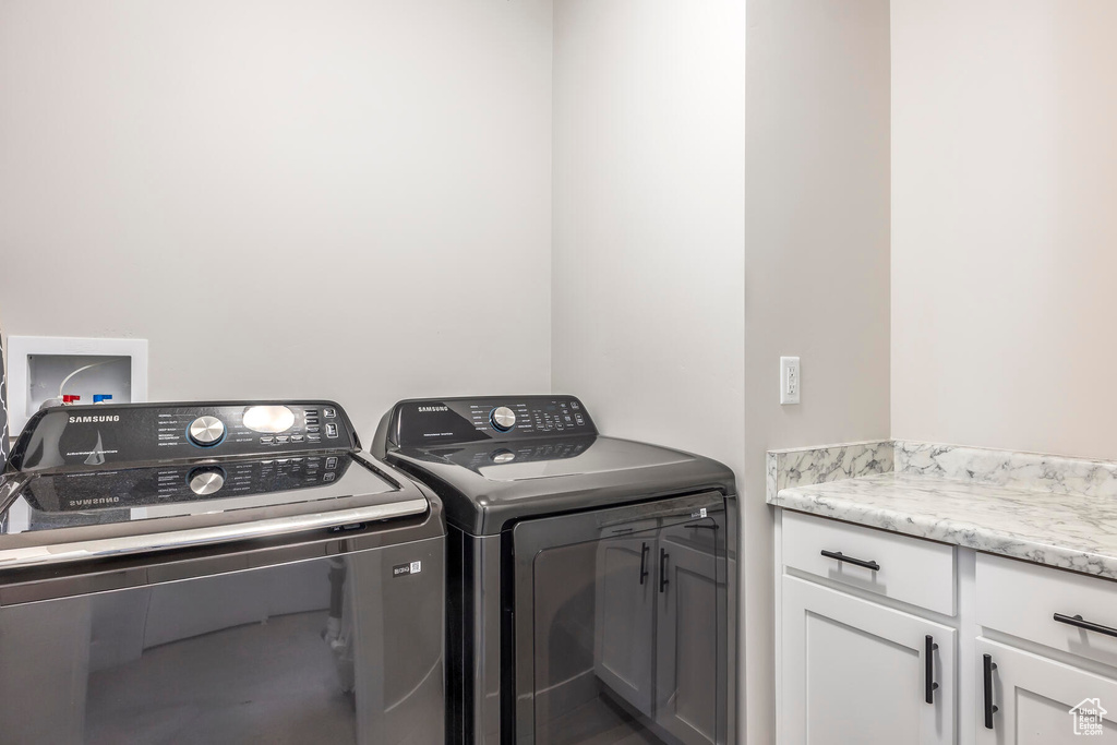 Laundry room featuring washer and clothes dryer, cabinets, and hookup for a washing machine