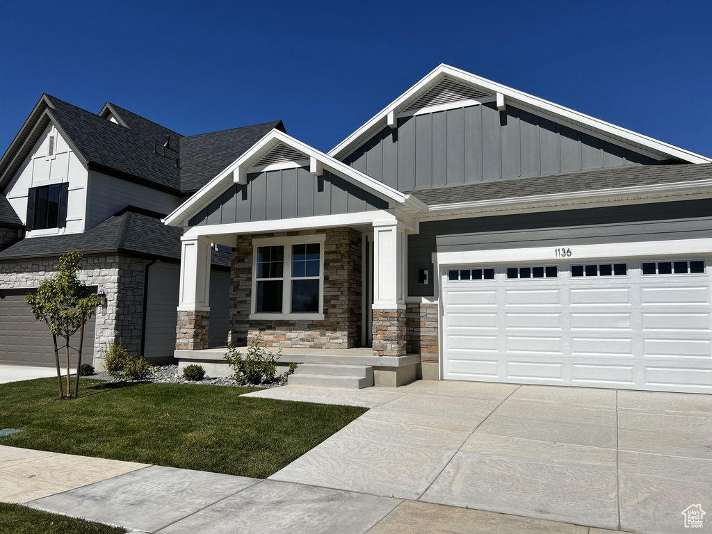 Craftsman inspired home featuring a front yard and a garage