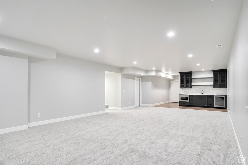 Unfurnished living room featuring light carpet and beverage cooler