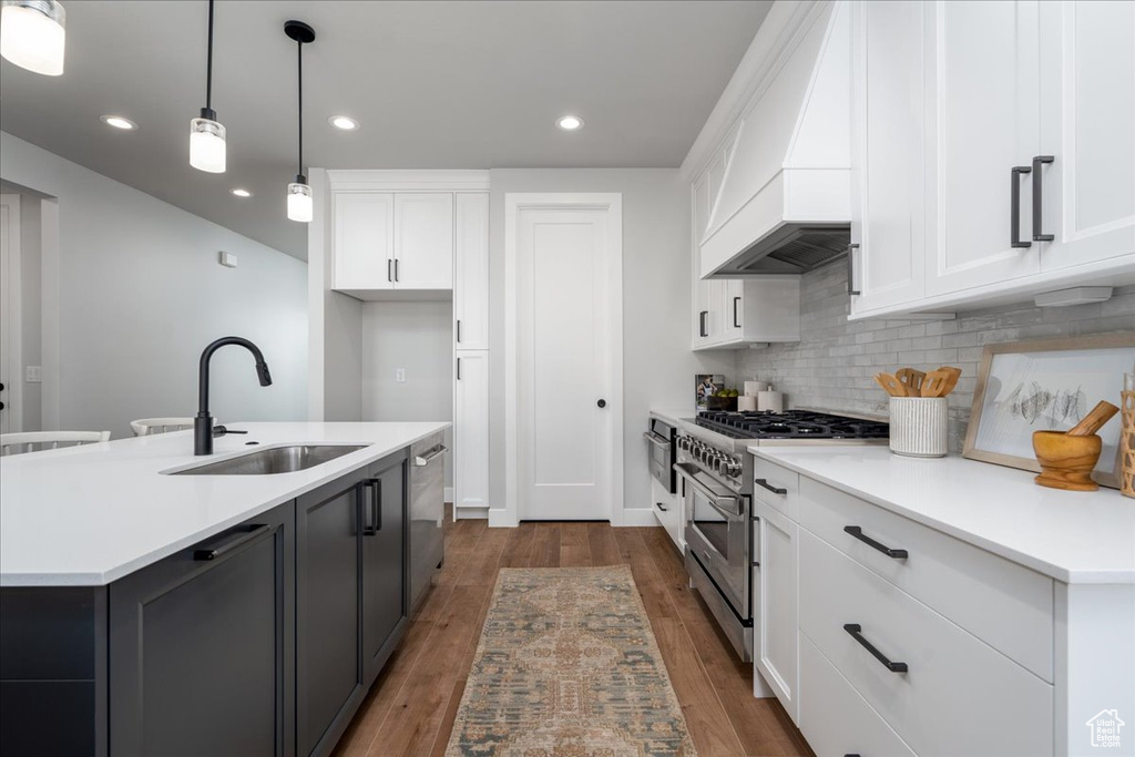 Kitchen with appliances with stainless steel finishes, pendant lighting, sink, and hardwood / wood-style floors