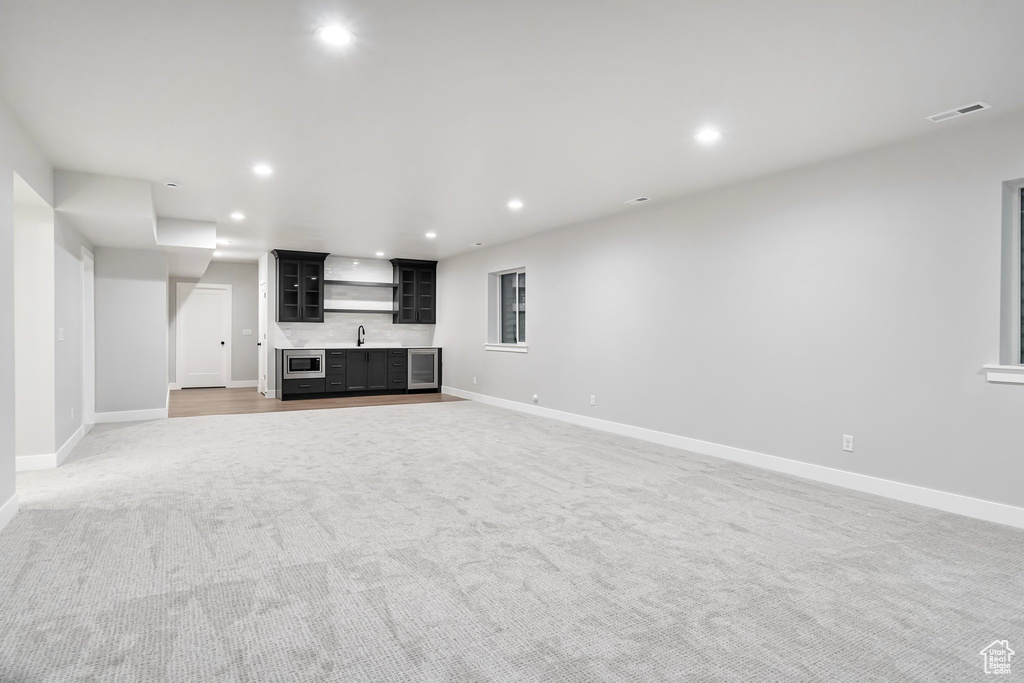 Unfurnished living room with sink and light carpet