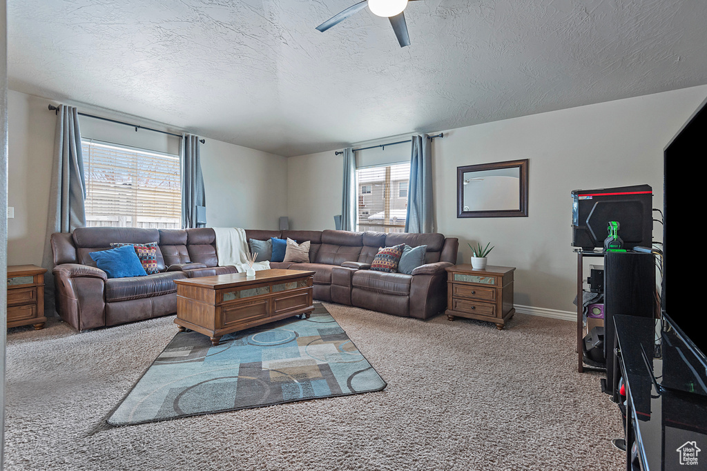 Living room featuring ceiling fan, a textured ceiling, light colored carpet, and plenty of natural light