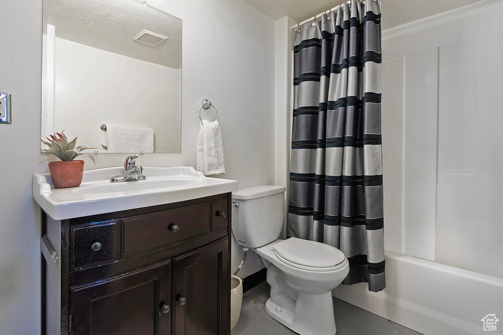 Full bathroom featuring toilet, vanity with extensive cabinet space, and shower / tub combo