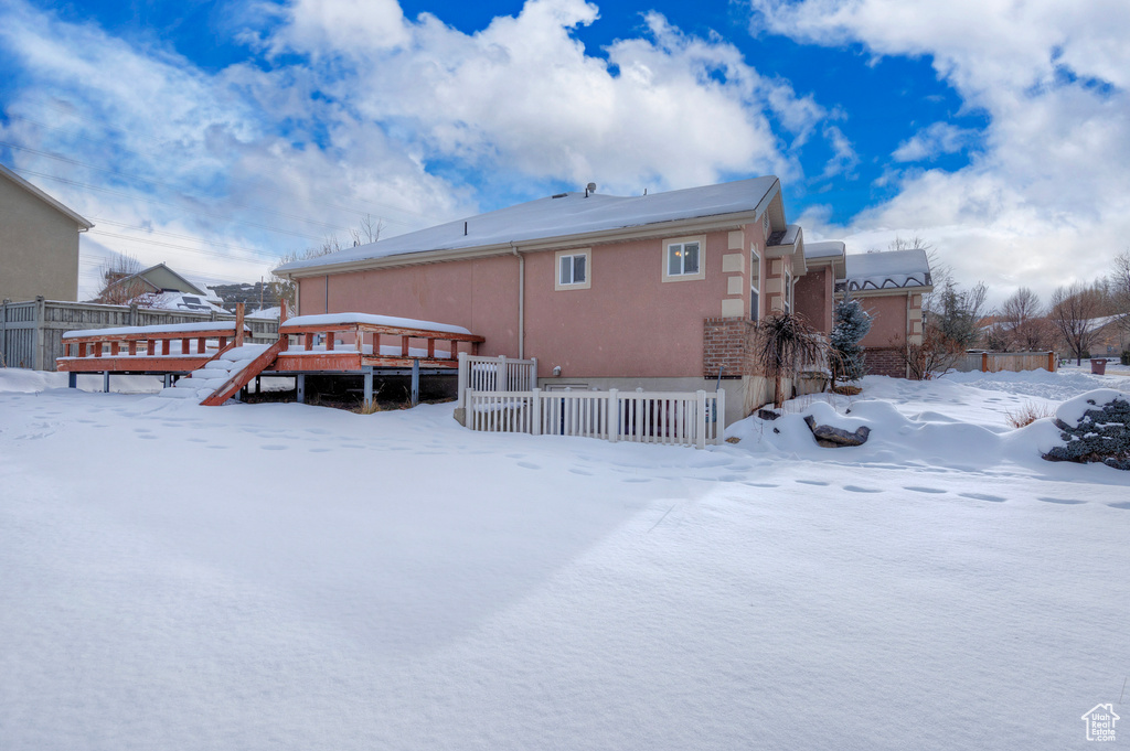 Snow covered rear of property featuring a wooden deck